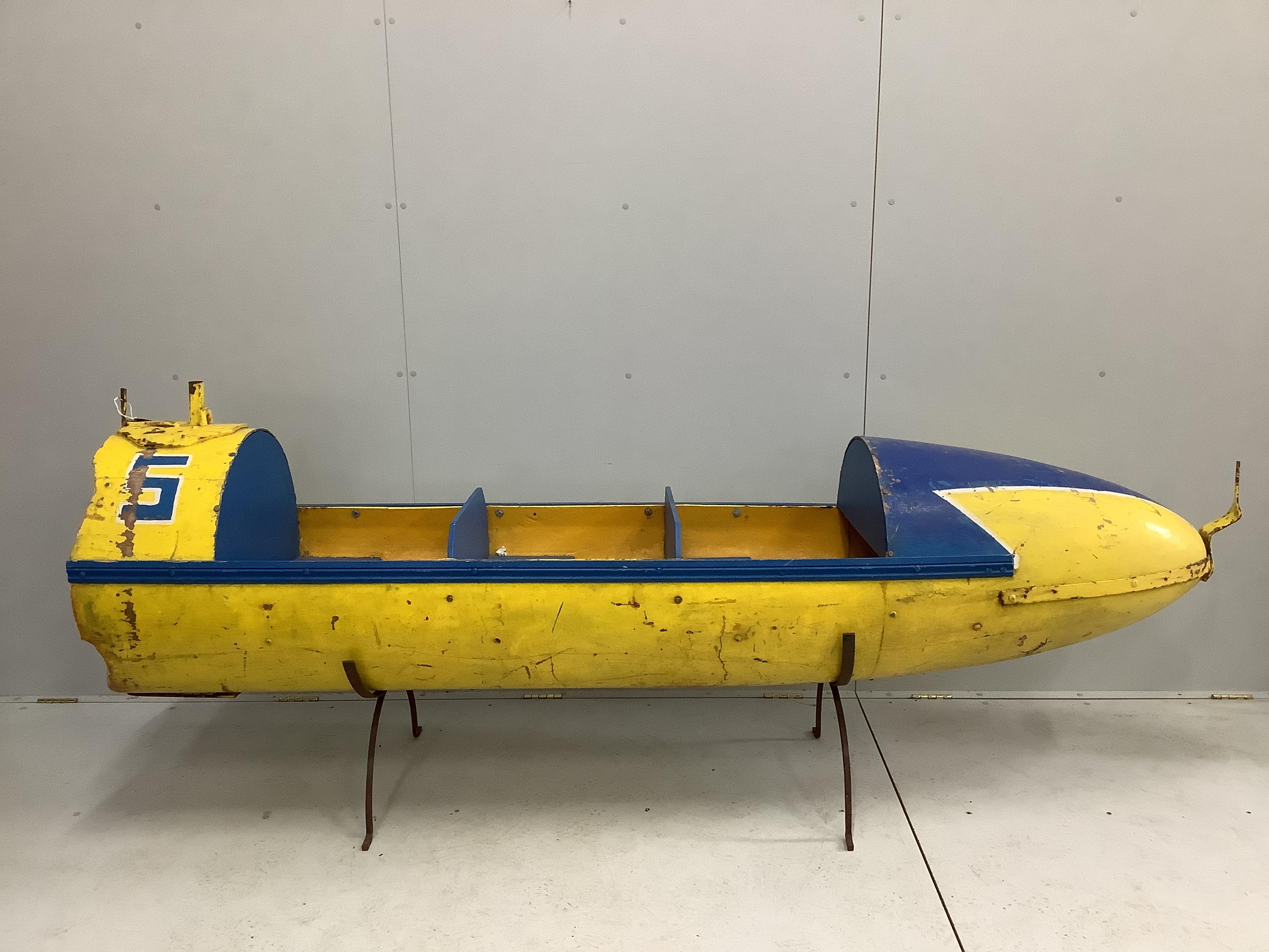 A vintage painted metal and wood torpedo shaped fairground ride seat, length 250cm, height 97cm